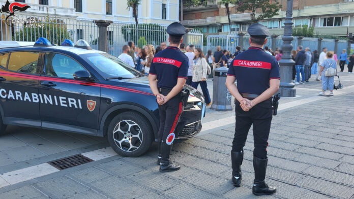 Carabinieri in divisa che parlano con uno studente di fronte a un istituto scolastico, immagine di archivio.