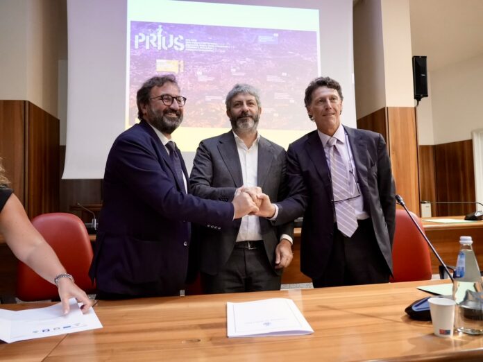 Firma accordo di programma rigenerazione urbana Avellino con tre uomini seduti al tavolo davanti a un proiettore in sala consiliare.