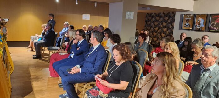 Gruppo di persone sedute a un tavolo in una sala conferenze con logo Lions Club proiettato su schermi sullo sfondo, immagine di archivio o illustrativa dell'evento.