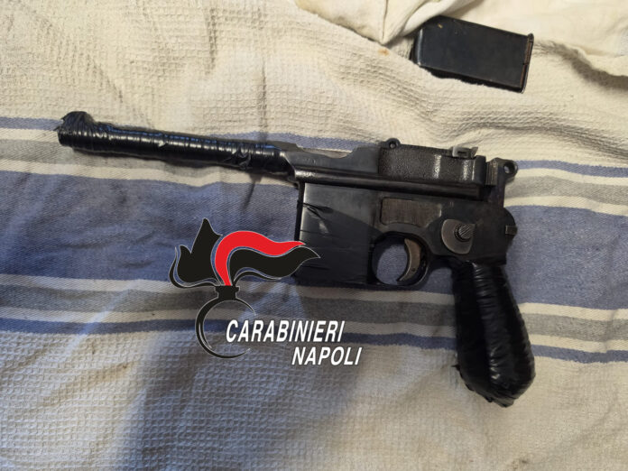 Pistola Mauser mod. 712 cal. 7,63 con silenziatore posta su una superficie tessile.