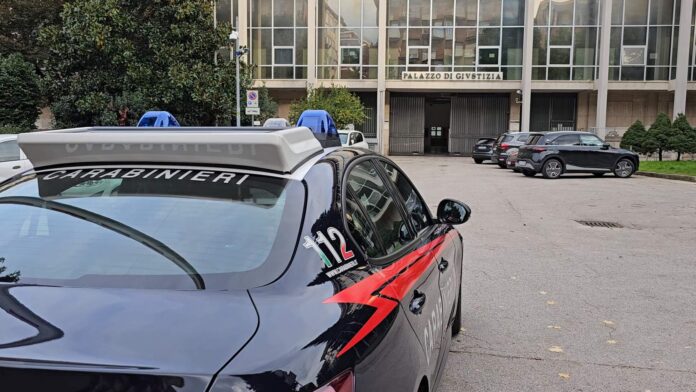 Auto dei Carabinieri parcheggiata davanti a un edificio del palazzo di giustizia.