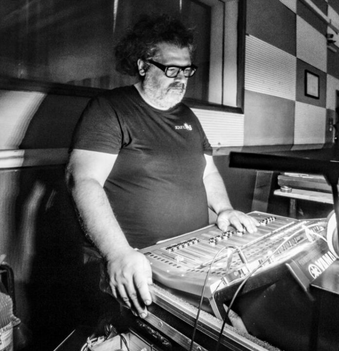 Foto in bianco e nero di un uomo che lavora con una consolle audio in uno studio musicale.