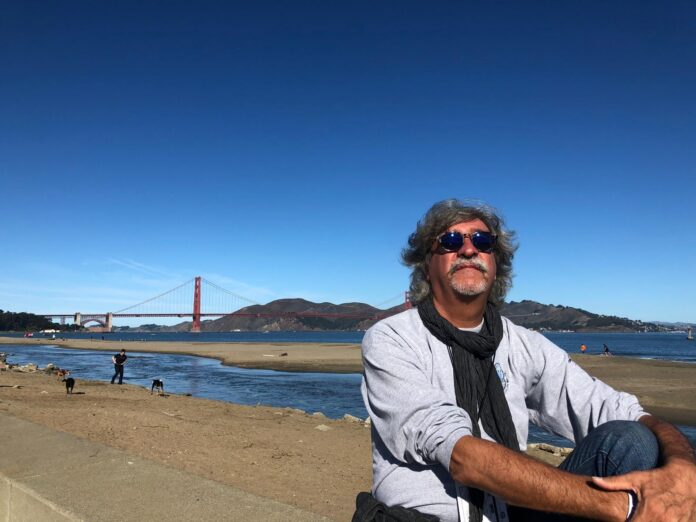 Foto panoramica del Golden Gate Bridge in California con cielo sereno e persona in primo piano.