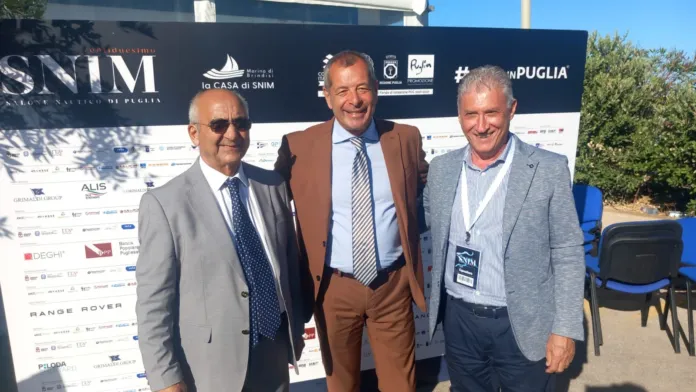 Tre persone in piedi davanti al pannello promozionale dello SNIM.