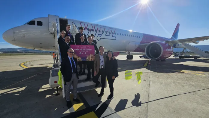 Un aereo Wizz Air sulla pista, con un gruppo di persone davanti alla scaletta.
