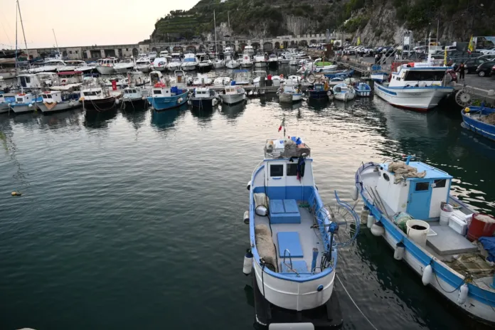 Fotografia di un porto con barche da pesca ormeggiate in acqua, scenario marittimo con molo e varie imbarcazioni.