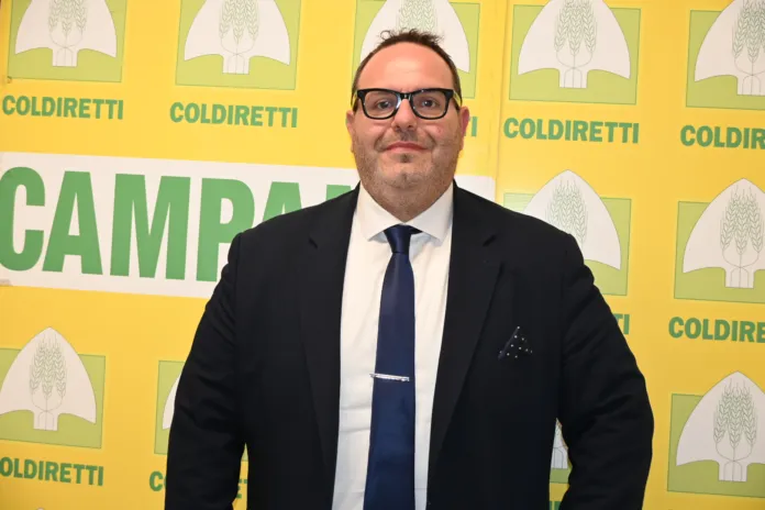 Roberto Mazzei in piedi davanti a un fondale con logo Coldiretti Campania, fotografia illustrativa della nomina al vertice.