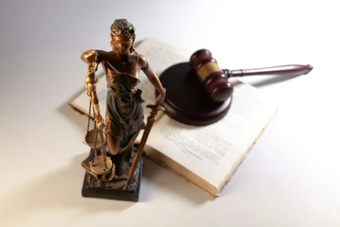 Statuetta della giustizia con bilancia e martelletto su libro, rappresentazione simbolica di una sentenza legale.