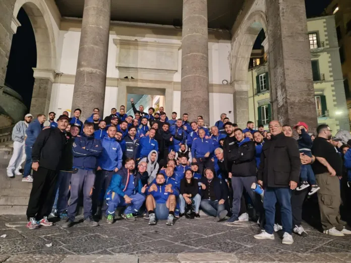 Un gruppo di persone, molte con giacche blu, posa davanti a un edificio con grandi colonne.