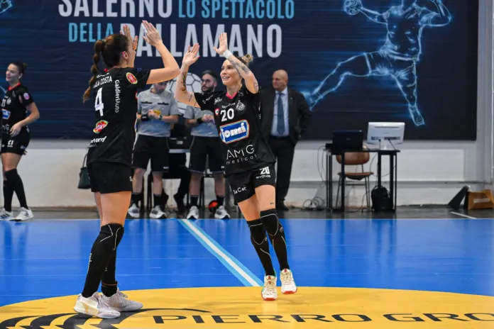 Due giocatrici della Jomi Salerno si danno il cinque durante una partita di pallamano in palestra.
