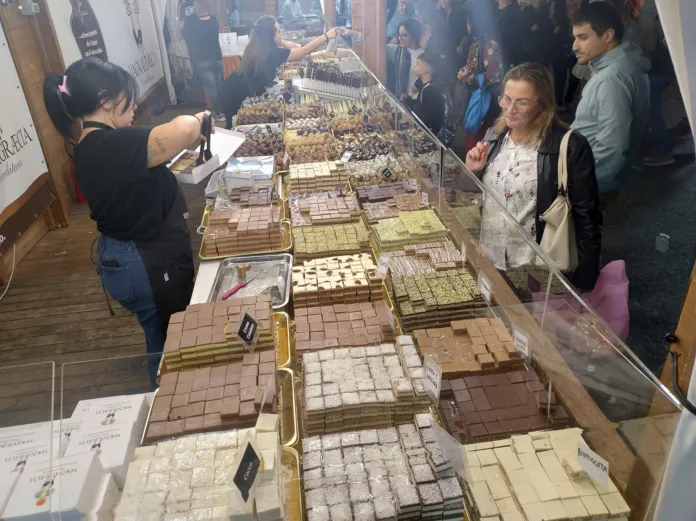 Dolci di diverse forme e colori disposti su vassoi e coperti da pellicola trasparente.