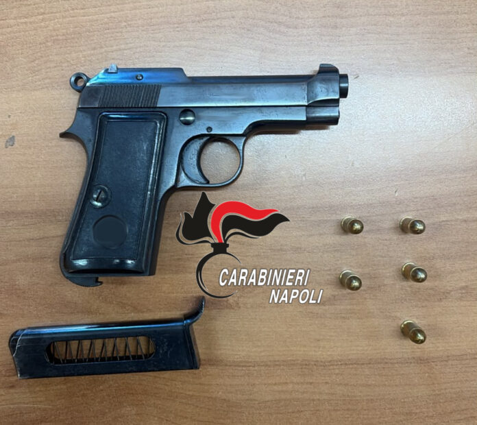 Pistola Beretta con caricatore e cinque proiettili disposti su un tavolo insieme a logo Carabinieri Napoli.