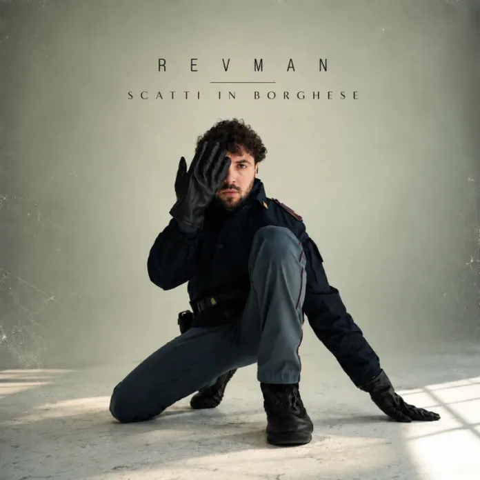 Un uomo in uniforme è inginocchiato in uno spazio illuminato; una mano gli copre parte del volto. Sullo sfondo compare la scritta “Revman – Scatti in borghese”.