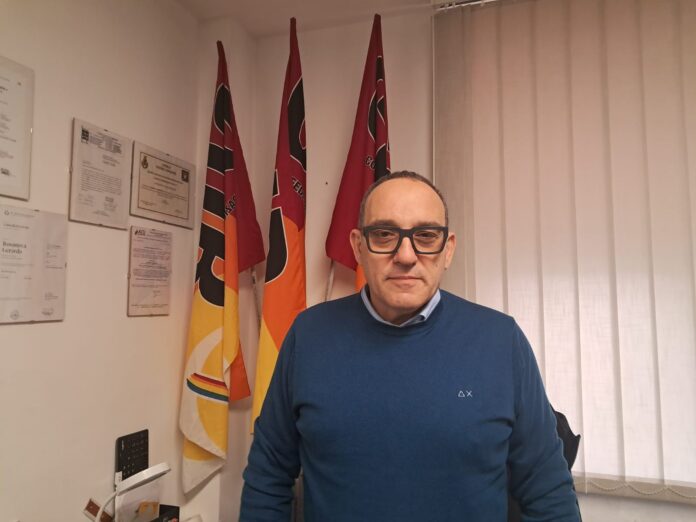 Gerardo Rosanova in piedi davanti ad alcune bandiere, foto fornita con il comunicato stampa.