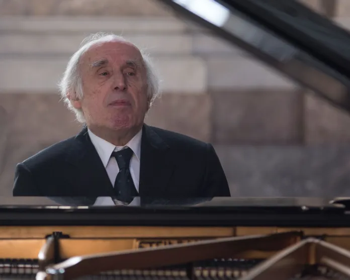 Immagine di Bruno Canino, famoso pianista, seduto al suo pianoforte durante un'esibizione.