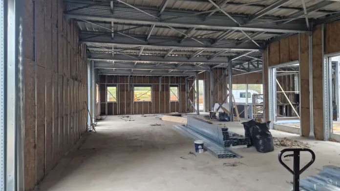 Interno di un edificio non completato, con struttura metallica visibile, pareti a vista e materiali da costruzione sul pavimento.
