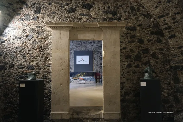 Ambiente con pareti in pietra, un’apertura incorniciata da elementi in pietra chiara e una sala sul fondo.