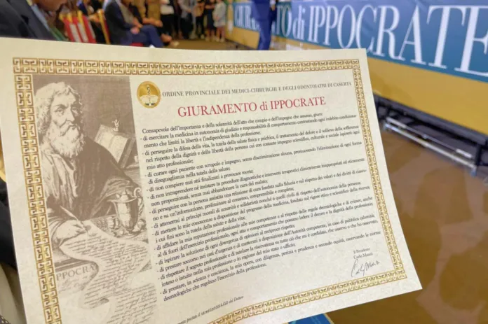 Attestato intitolato «Giuramento di Ippocrate» appoggiato su un tavolo; sullo sfondo si vede uno striscione con la scritta «Giuramento di Ippocrate».