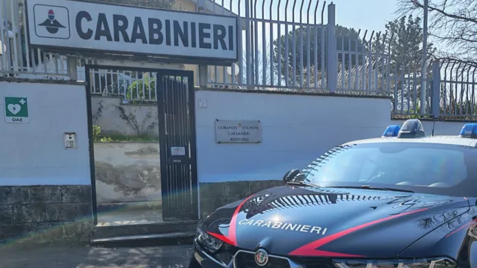 Un’auto dei Carabinieri davanti a un cancello e a un’insegna con la scritta «Carabinieri».