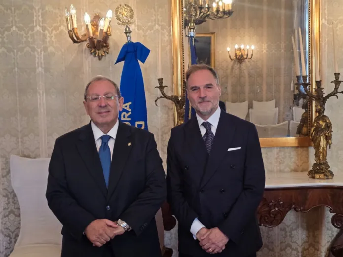 Due uomini in abito elegante in un ambiente interno formale.