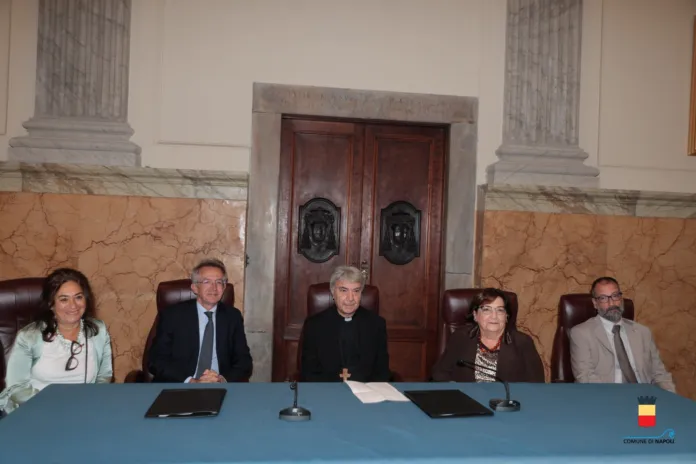 Cinque persone sedute dietro un tavolo azzurro, con microfoni e documenti.