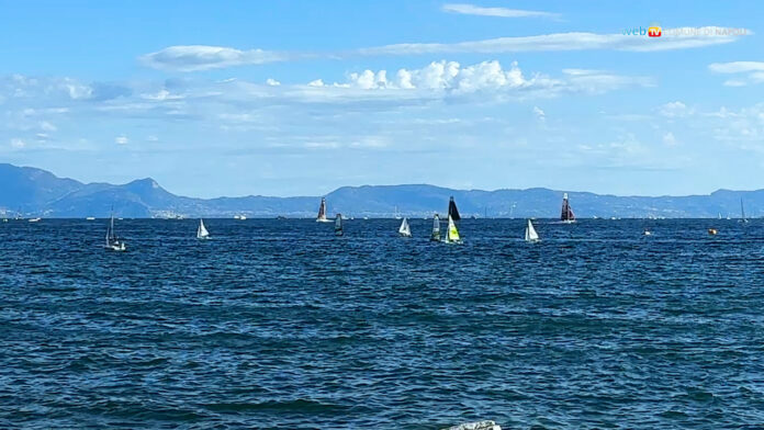 Vista sul mare del golfo di Napoli con barche a vela in regata e cielo sereno.