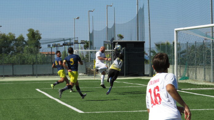 Calciatori durante una partita su campo in erba sintetica vicino alla porta.