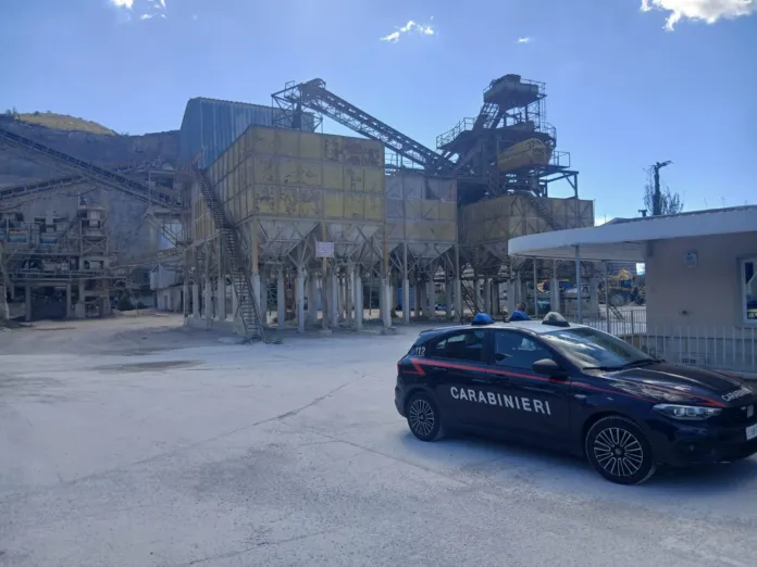Cava calcarea con impianto industriale e auto dei carabinieri nel piazzale