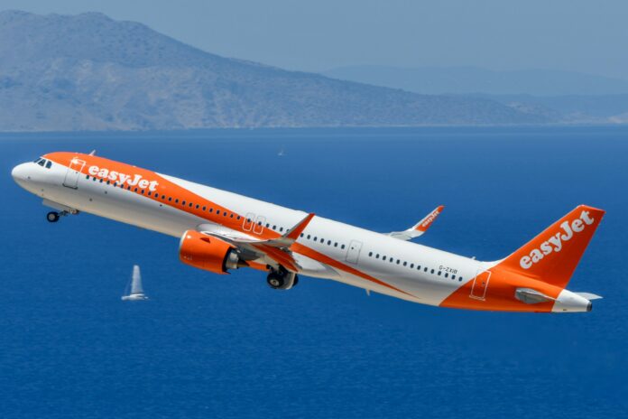 Aereo easyJet arancione e bianco in aria sopra il mare, fotografia illustrativa.