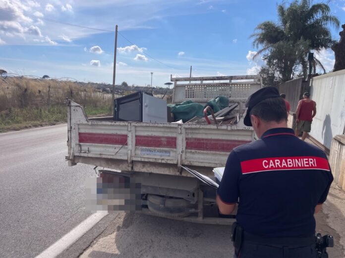 Forze dell'ordine che controllano un veicolo con rifiuti su una strada in campagna.