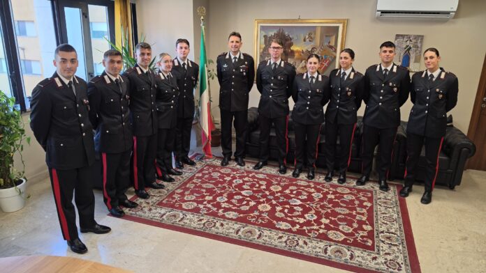 Dieci Allievi Marescialli in uniforme in piedi in una stanza con bandiera italiana.