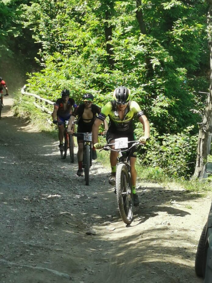 Ciclisti in mountain bike durante una gara nel Parco Regionale dei Monti Lattari, su un sentiero sterrato immerso nella vegetazione.