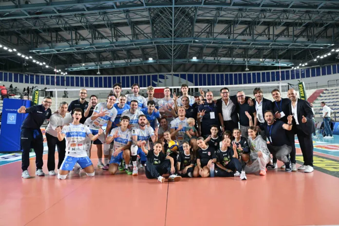 Immagine di una squadra di pallavolo che festeggia la vittoria con la propria tifoseria al palazzetto dello sport.
